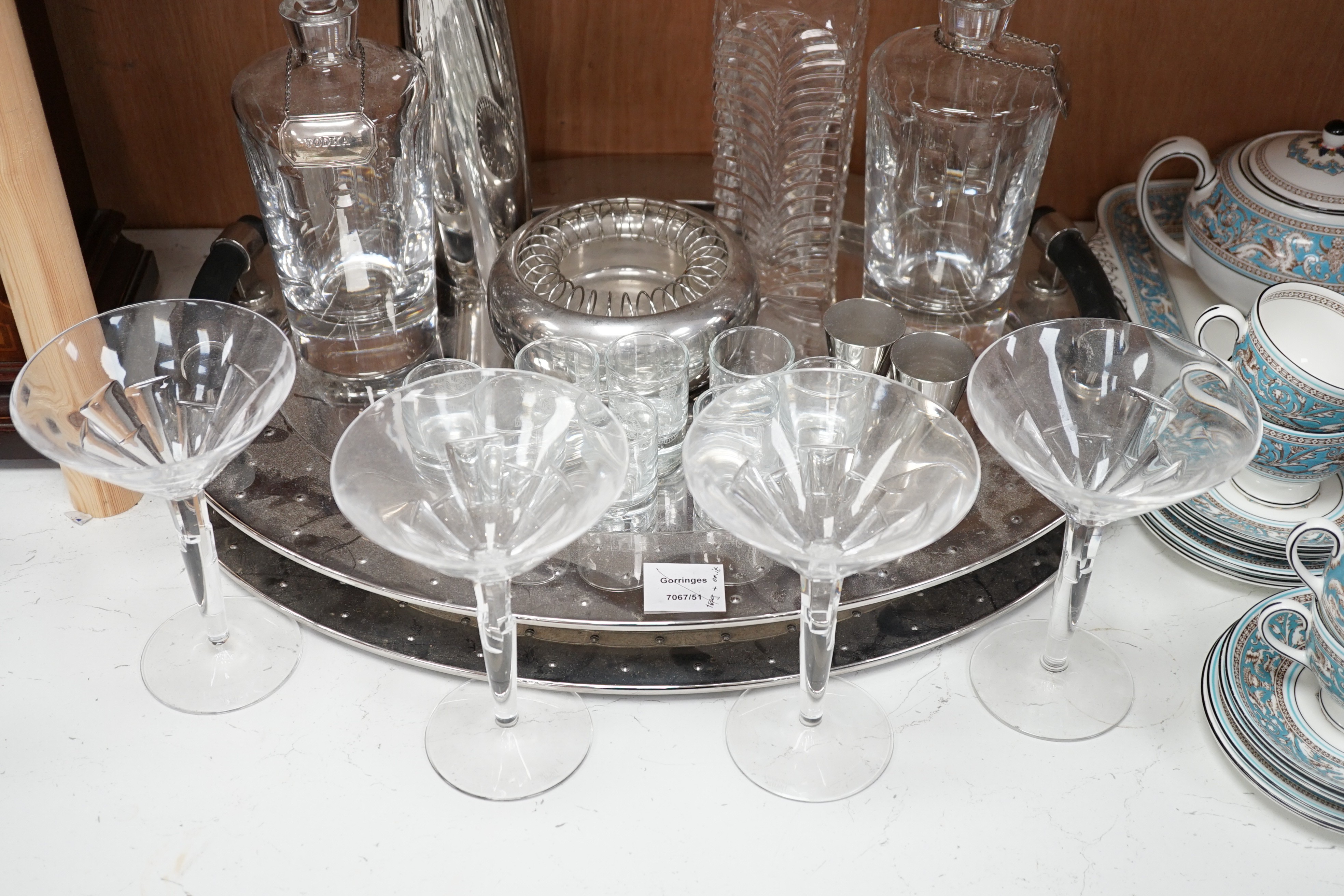 A stylish oval chromed metal two handled tray, with assorted decanters, glassware and cocktail equipment, 56 cms wide